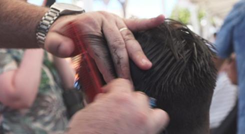 Un client tallant-se el cabell per la investigació del càncer infantil